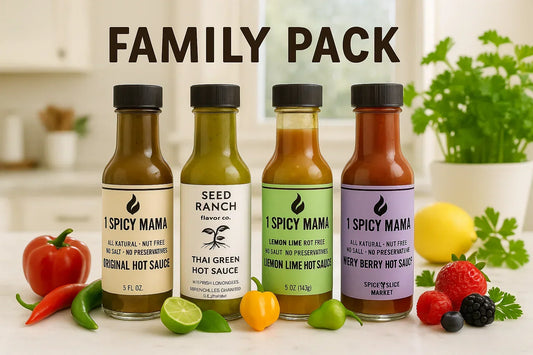 Family pack of four hot sauce bottles with fresh peppers, lime, and berries on kitchen counter