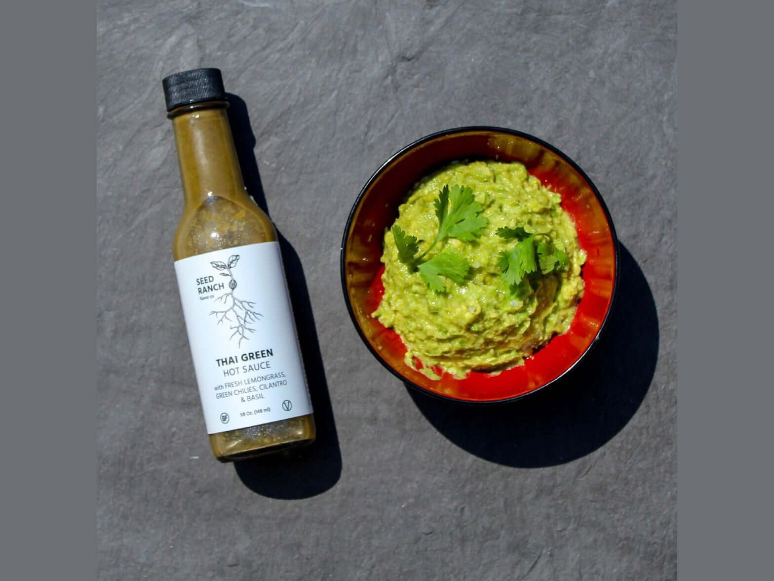 Classic Heat Trio - 3 Bottle Bundle featuring Thai Green hot sauce and a bowl of guacamole.