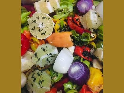 Colorful mix of sliced lemons, red and green peppers, onion, and herbs for cooking