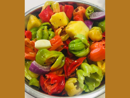 Colorful chopped peppers, onion, garlic, and pineapple in a metal bowl for cooking