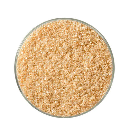 Close-up of light brown raw sugar crystals in a round glass container on white background