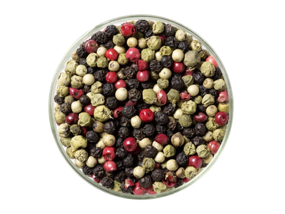 Mixed peppercorns in a clear glass bowl on white background