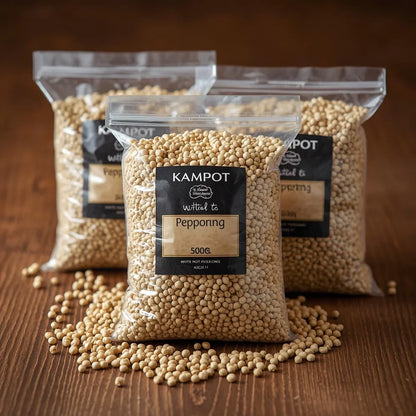 Three clear bags of Kampot white peppercorns on wooden surface, one spilled