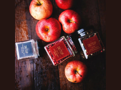 Salt's Up spice jars and red apples on rustic wooden table