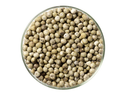 Round glass bowl filled with whole white peppercorns on a white background