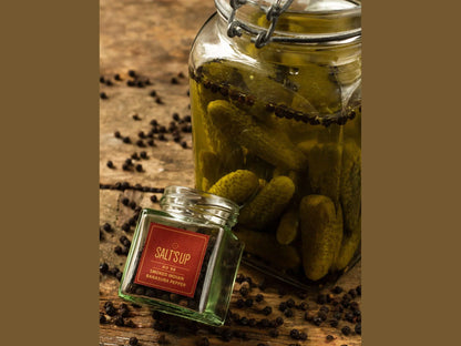 Glass jar of pickles and SALT'S UP smoked Indian Banasura pepper on rustic wooden table