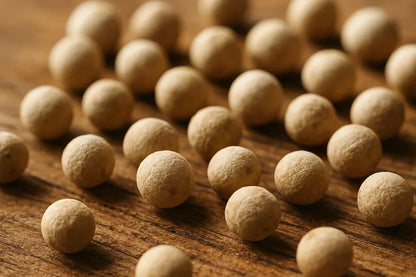 Macro close-up of whole white peppercorns on rustic wooden surface
