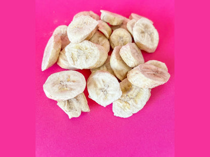 Dried banana chips piled on a bright pink background, healthy snack food