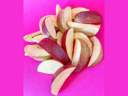 Dried apple slices with red peel on bright pink background, healthy fruit snack