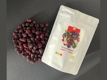 White pouch of freeze-dried organic blackberries with scattered freeze-dried berries on black surface